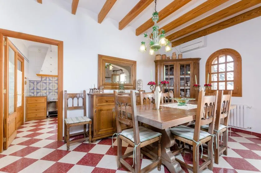 A dining room with a wooden table and chairs beneath exposed ceiling beams.
