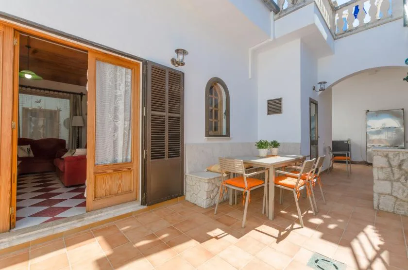 A dining area with a table and chairs sits beside an open doorway.