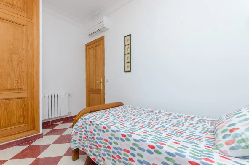 A bedroom with a bed covered in colorful patterned bedding.