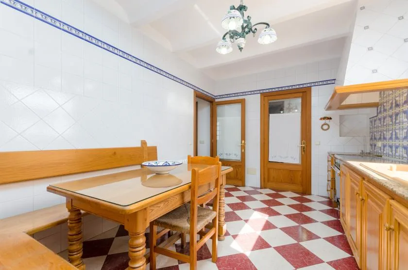 A tiled kitchen and dining area with wooden cabinetry and a table.