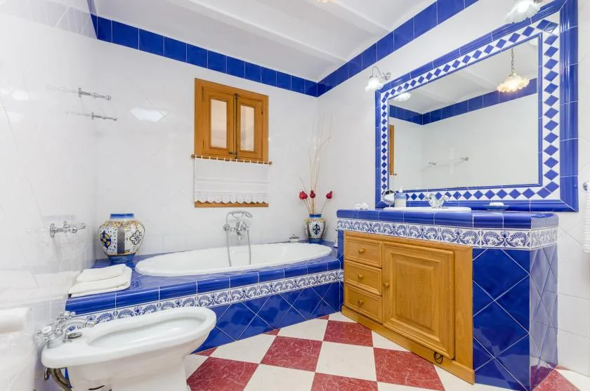 A tiled bathroom with a bathtub, sink, and wooden vanity beneath a large mirror.
