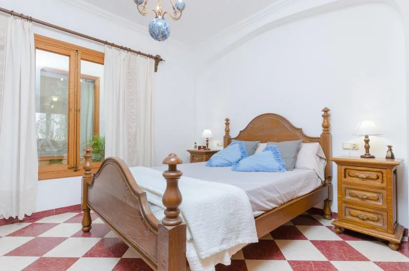 A bedroom with a wooden bed, blue pillows, and a checkered floor.
