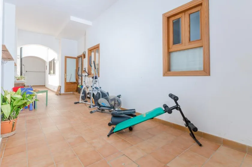 A bright indoor exercise area with workout equipment along the wall.