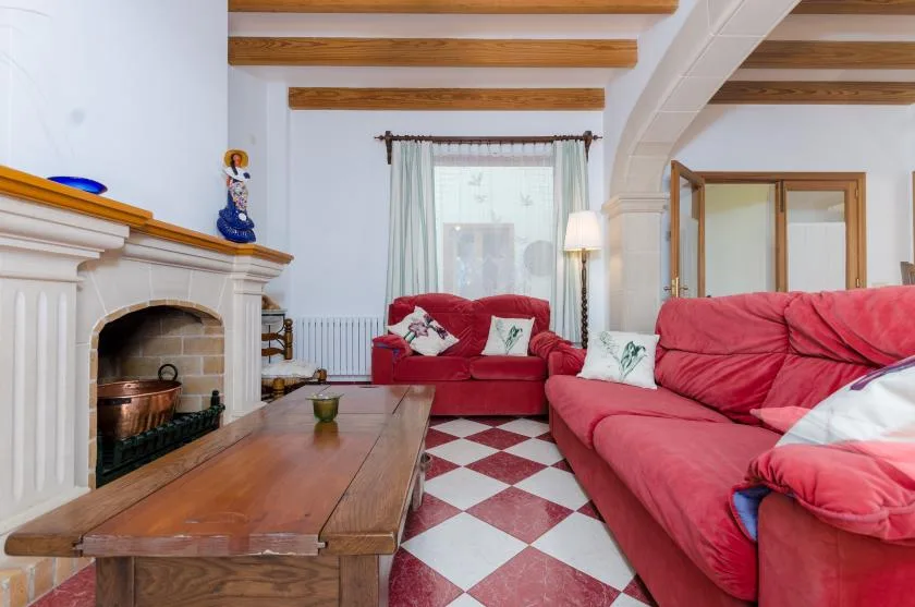 A living room with red seating, a fireplace, and a wooden coffee table.