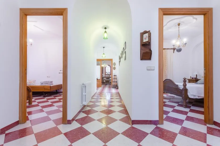 A tiled hallway connects two bedrooms, with wooden doorways along the corridor.