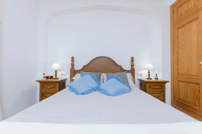 A bedroom with a wooden bed, blue pillows, and matching bedside tables.
