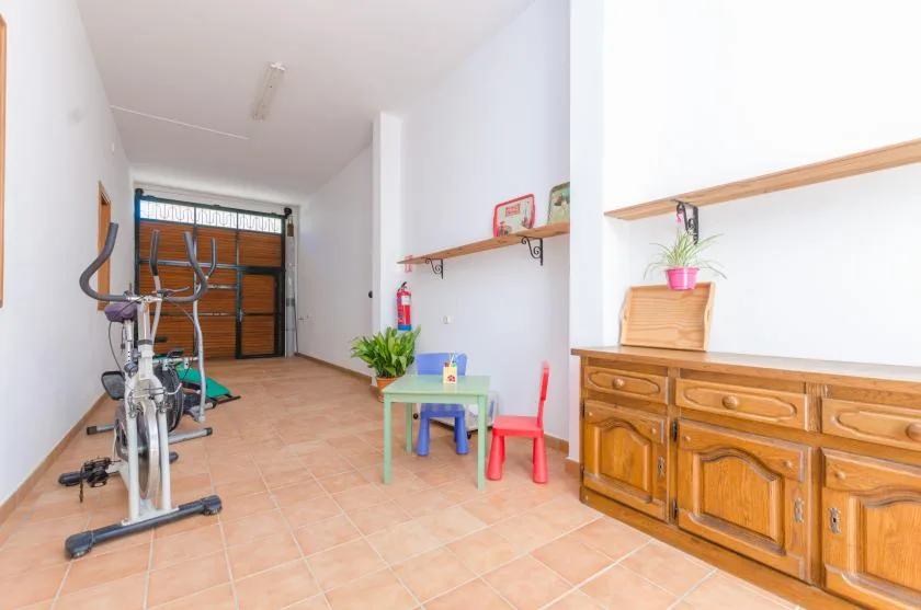 A bright room with exercise equipment, a small table, and wooden cabinets.
