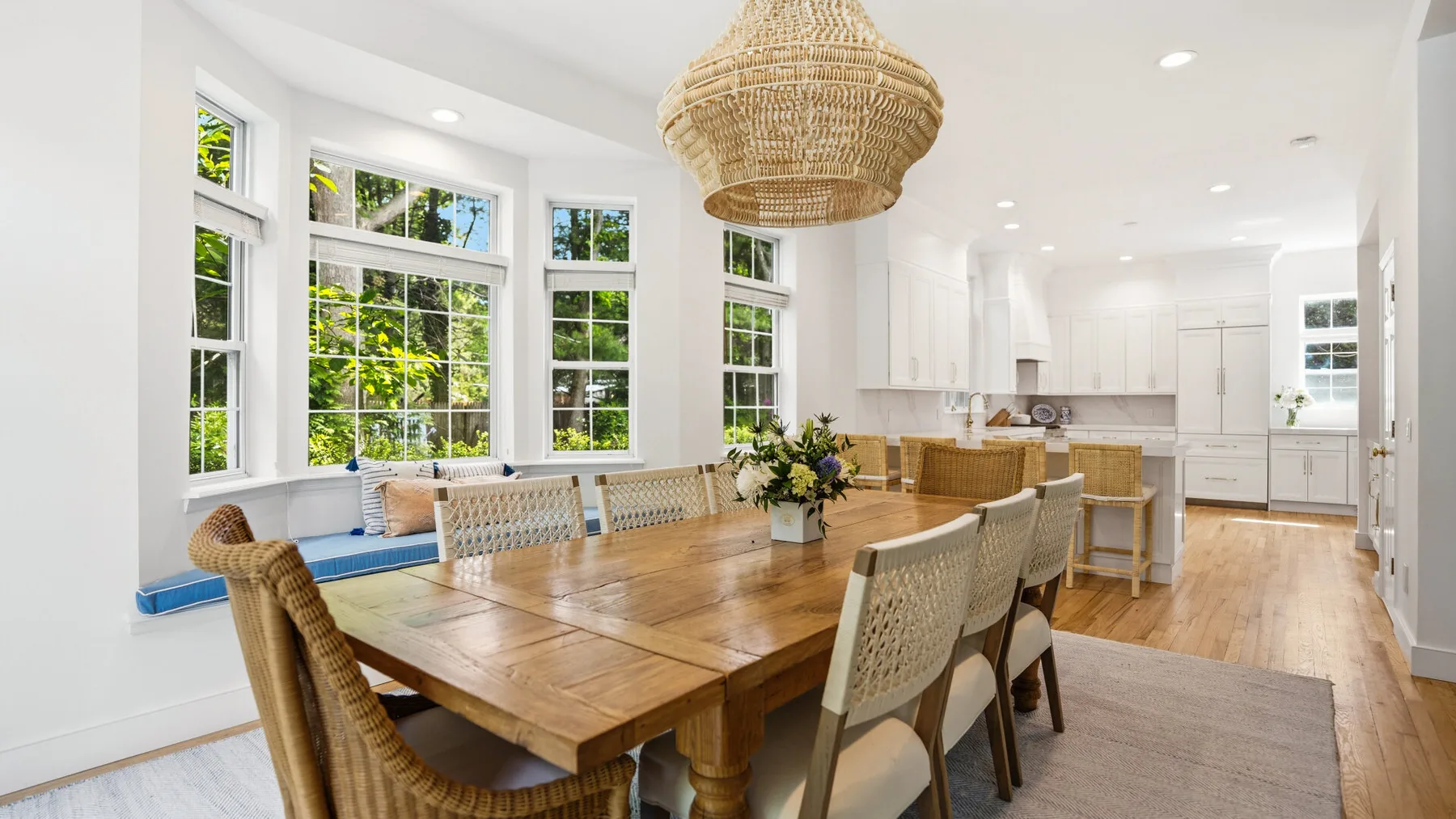 Un comedor luminoso con una larga mesa de madera junto a grandes ventanas.