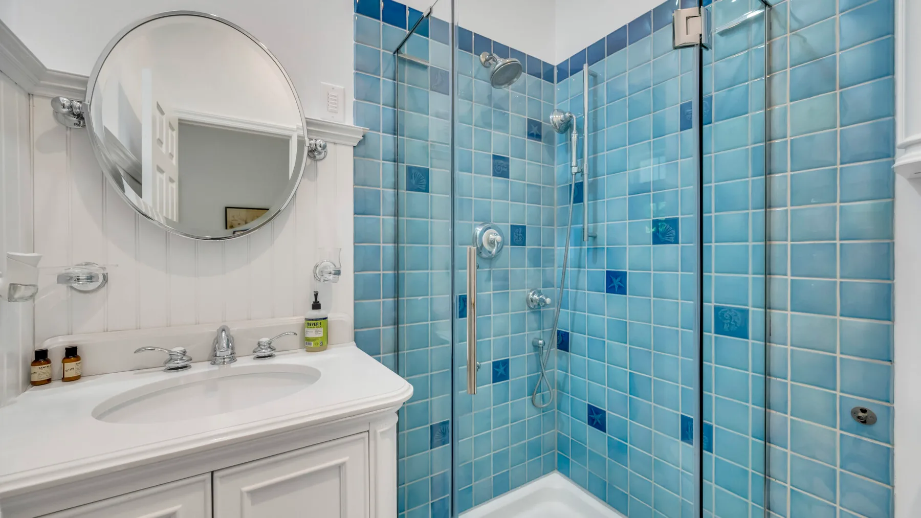Un baño con una ducha de vidrio y un lavabo blanco con mueble.
