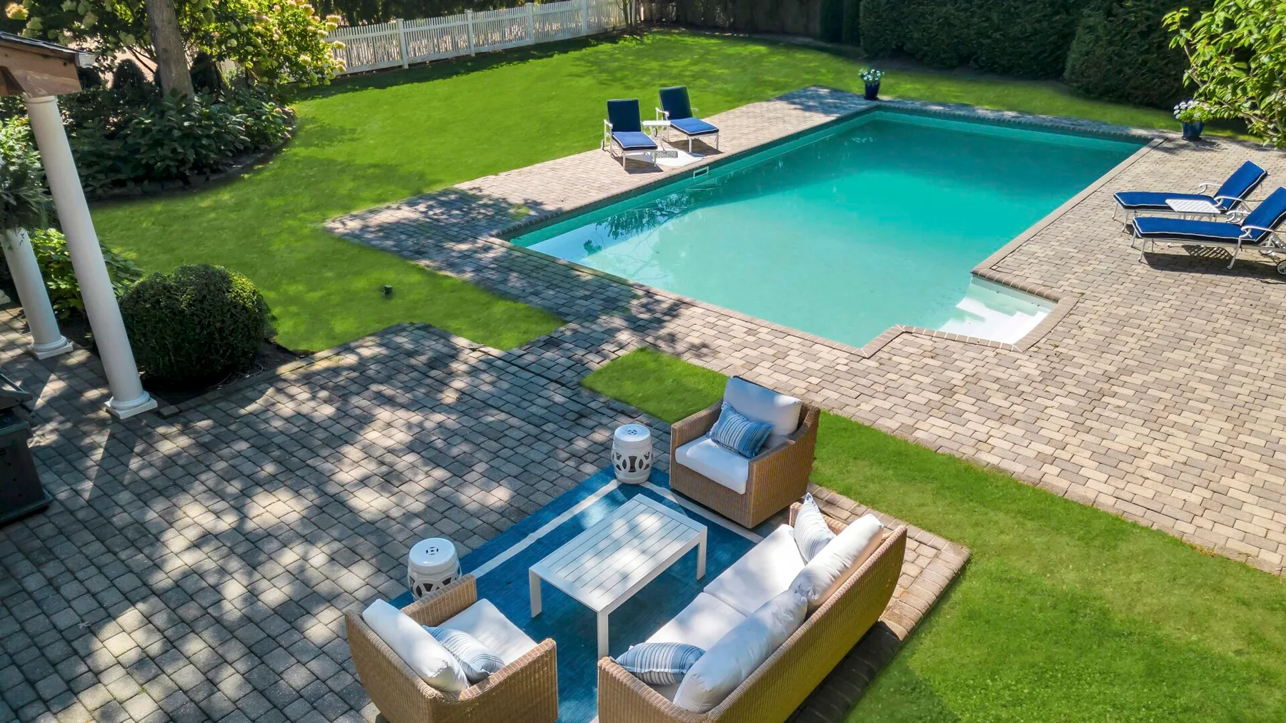Una piscina en el patio está rodeada de zonas pavimentadas para sentarse y césped.