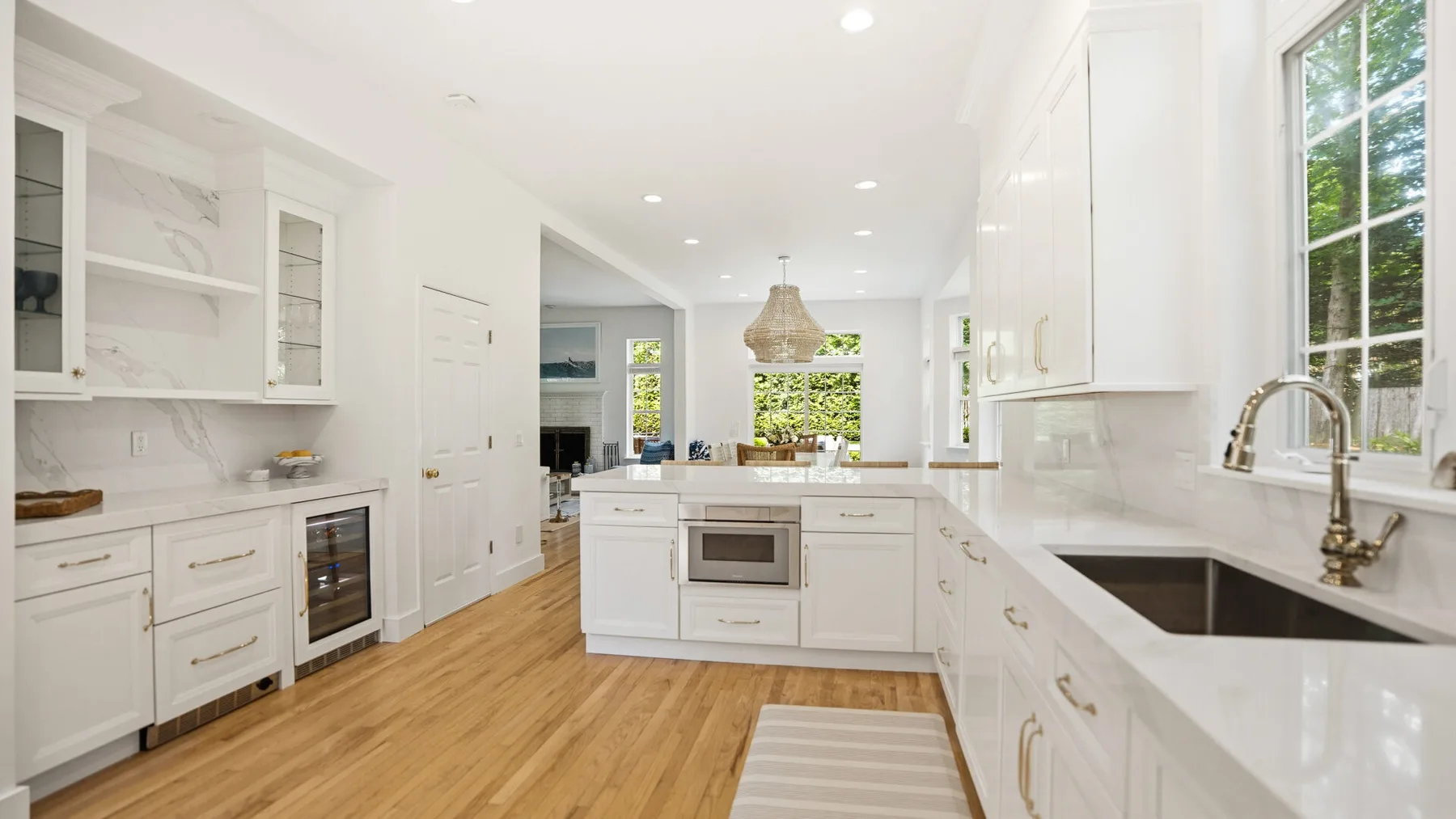 Una cocina blanca y luminosa con una isla central y ventanas grandes.