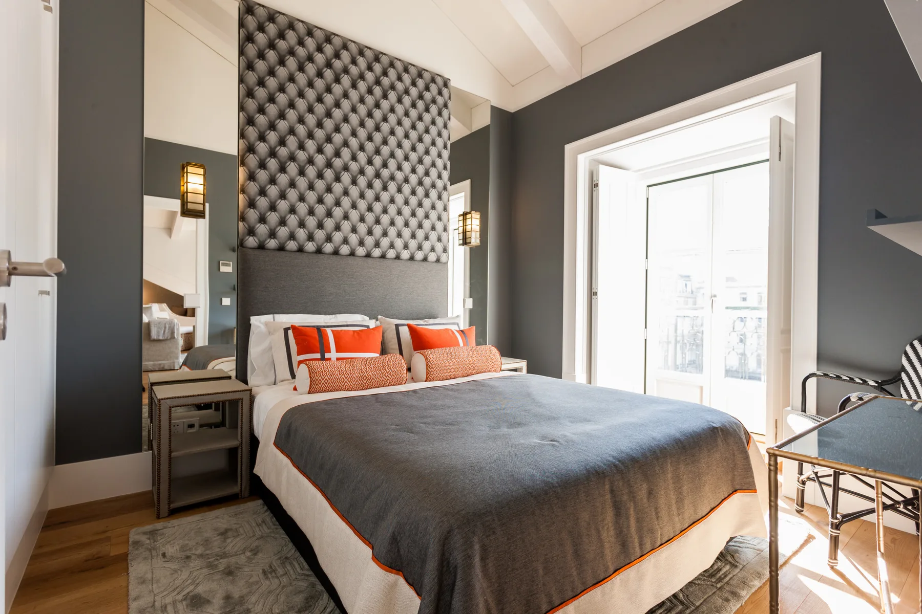 Un dormitorio con la cama tendida y una ventana luminosa.