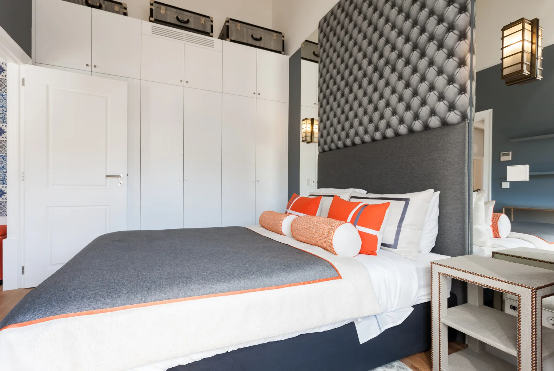 Un dormitorio con una cama vestida con ropa de cama gris y naranja.