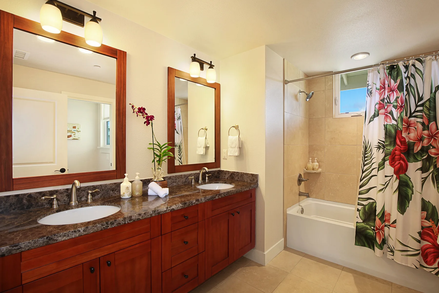 Un baño con un lavabo doble y una bañera detrás de una cortina floral.