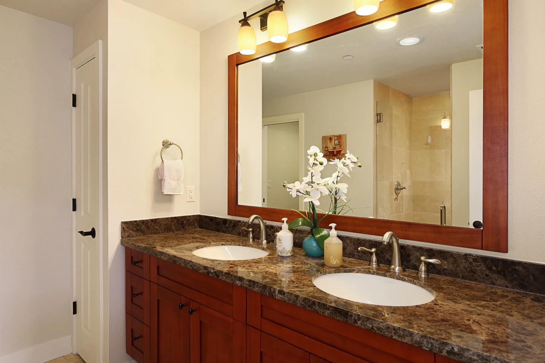 Un tocador de baño con dos lavabos está bajo un espejo grande.