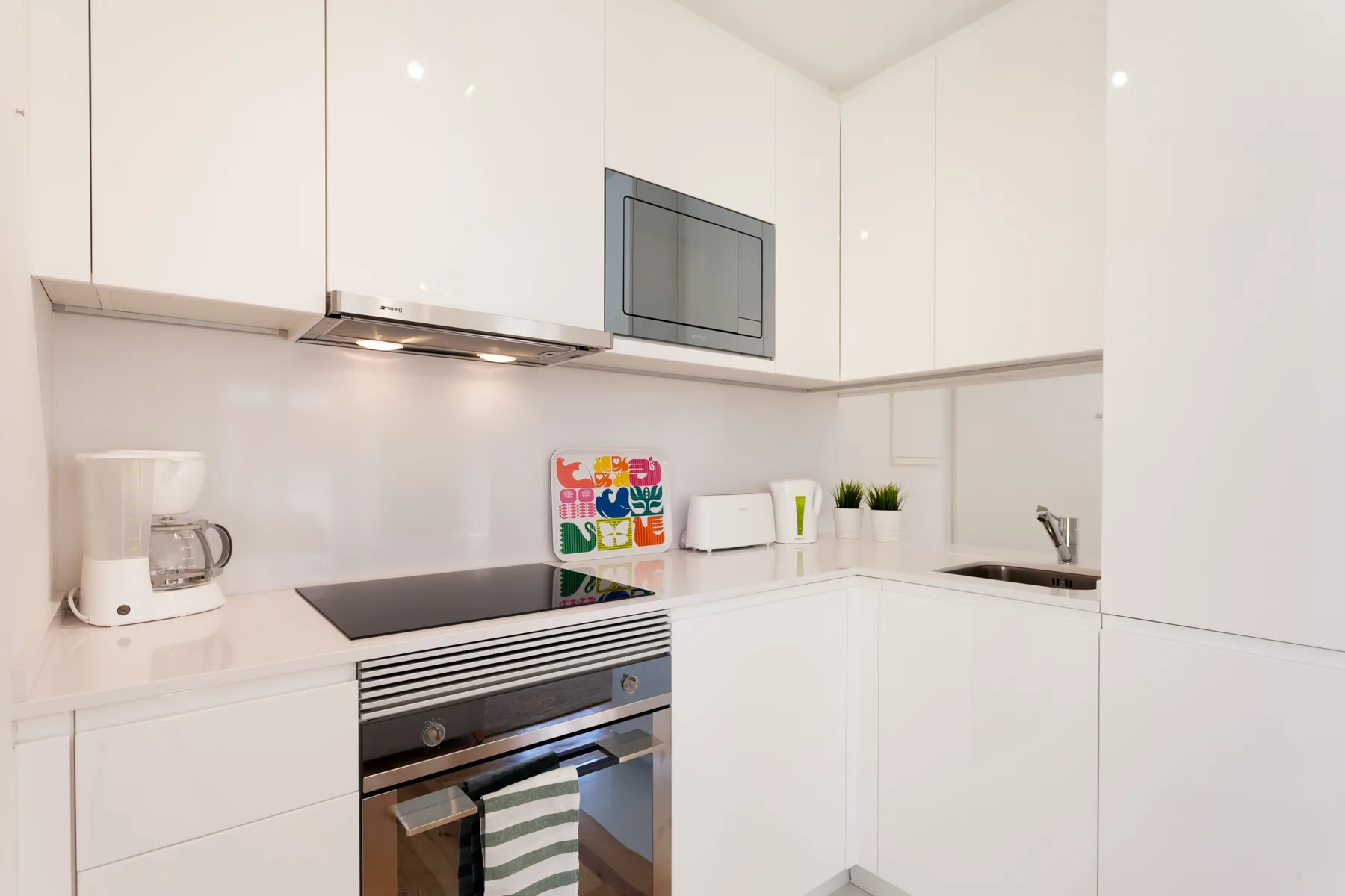 A bright white kitchen with an oven, cooktop, and countertop appliances.