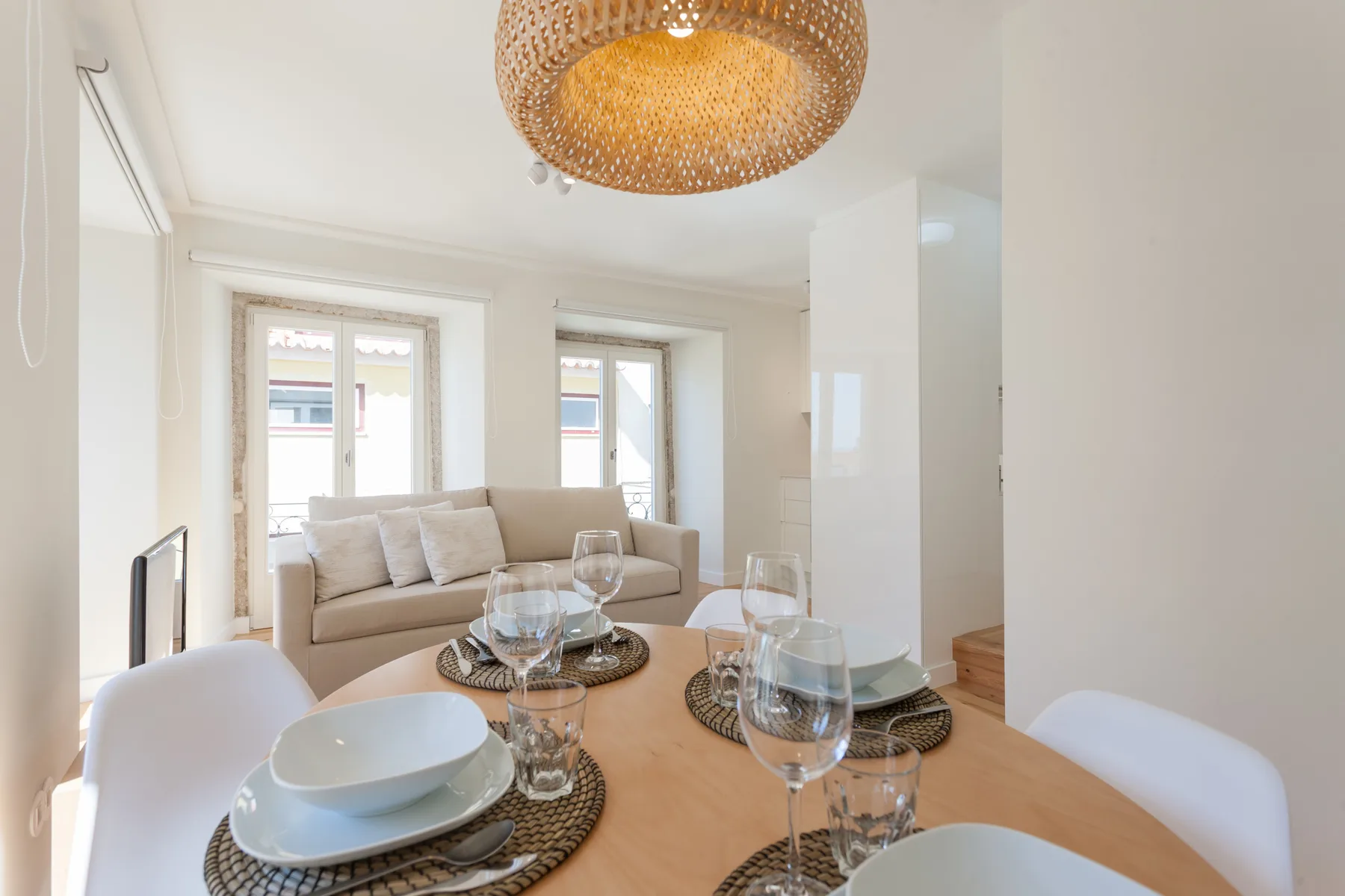 A bright living and dining area with a sofa, table, and large windows.