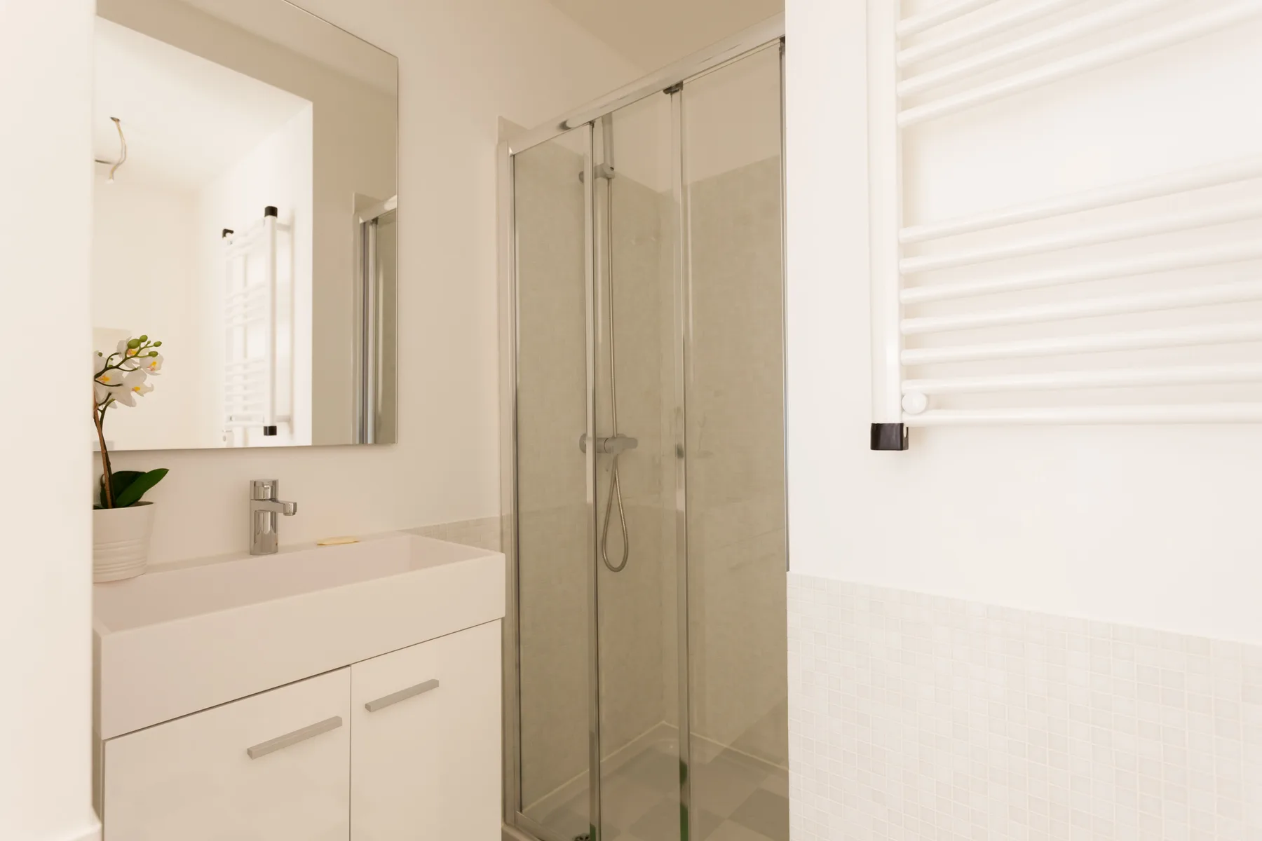 A bright bathroom with a sink and shower.