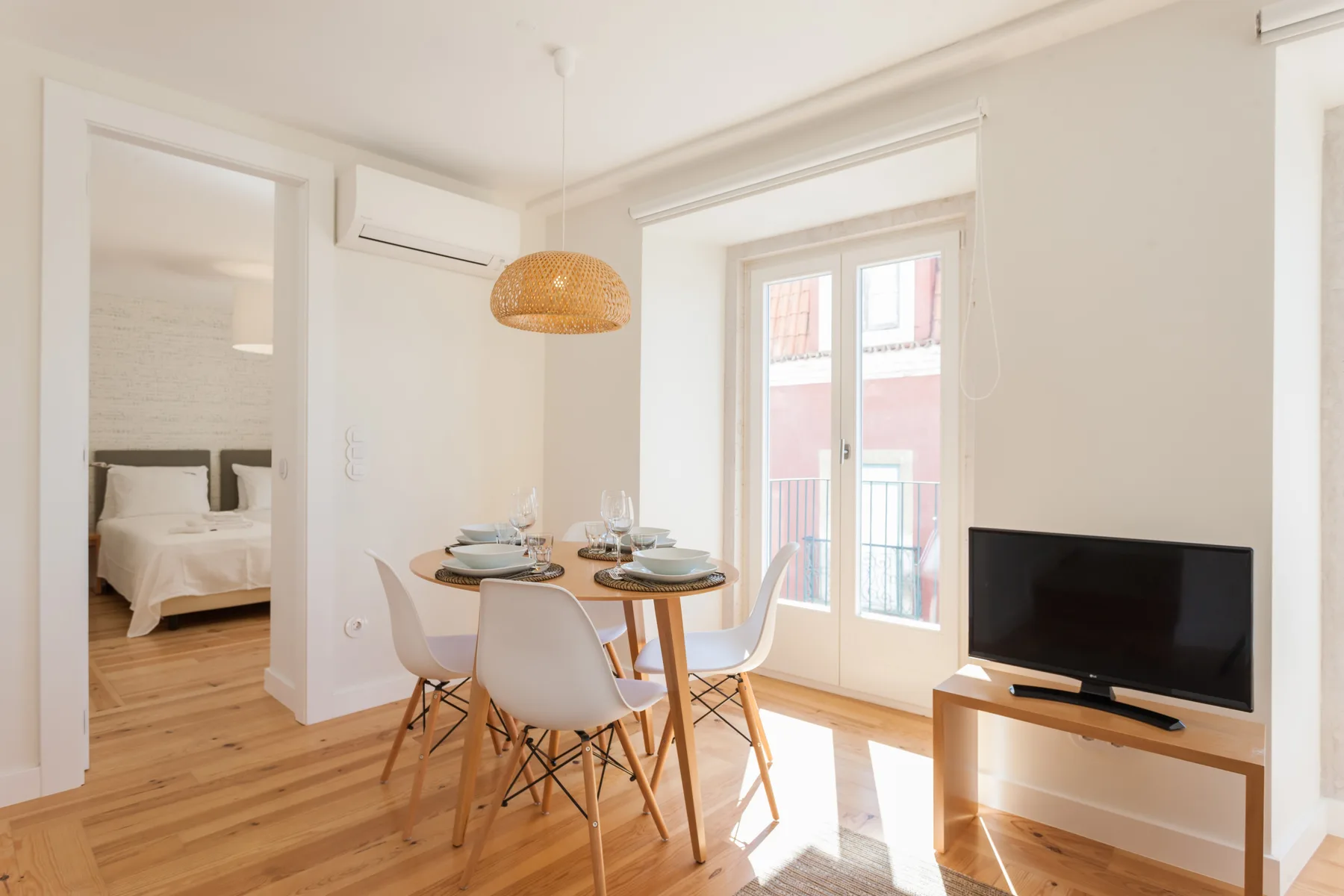 A bright dining and living area with a table, seating, and a television.