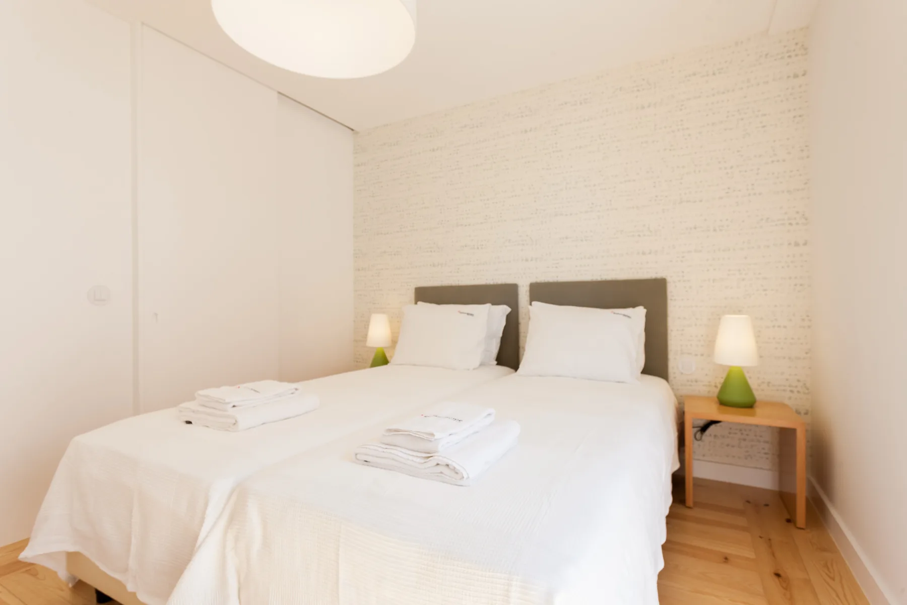 A bedroom with a double bed, white bedding, and bedside lamps.