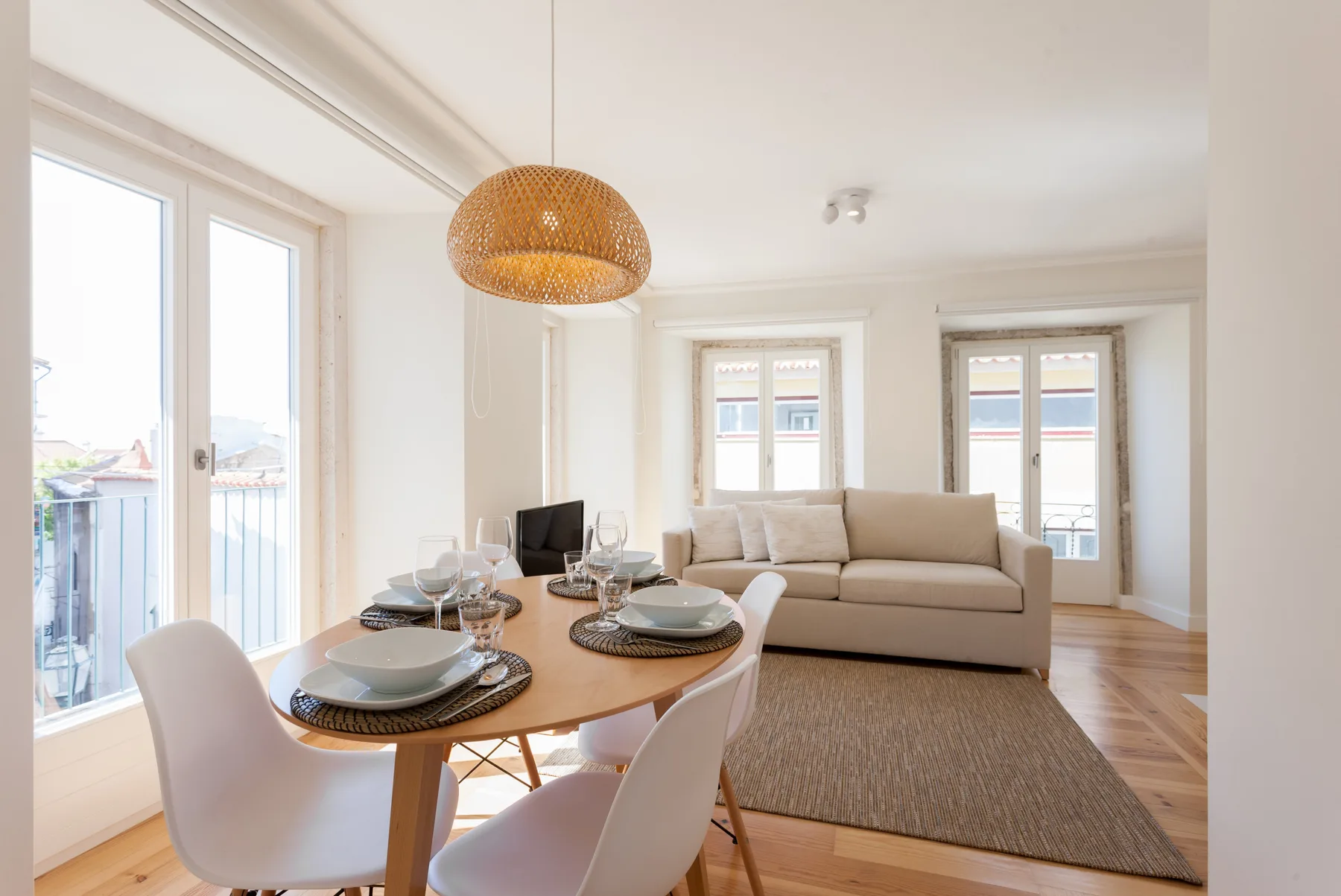 A bright living and dining area with a table, seating, and large windows.