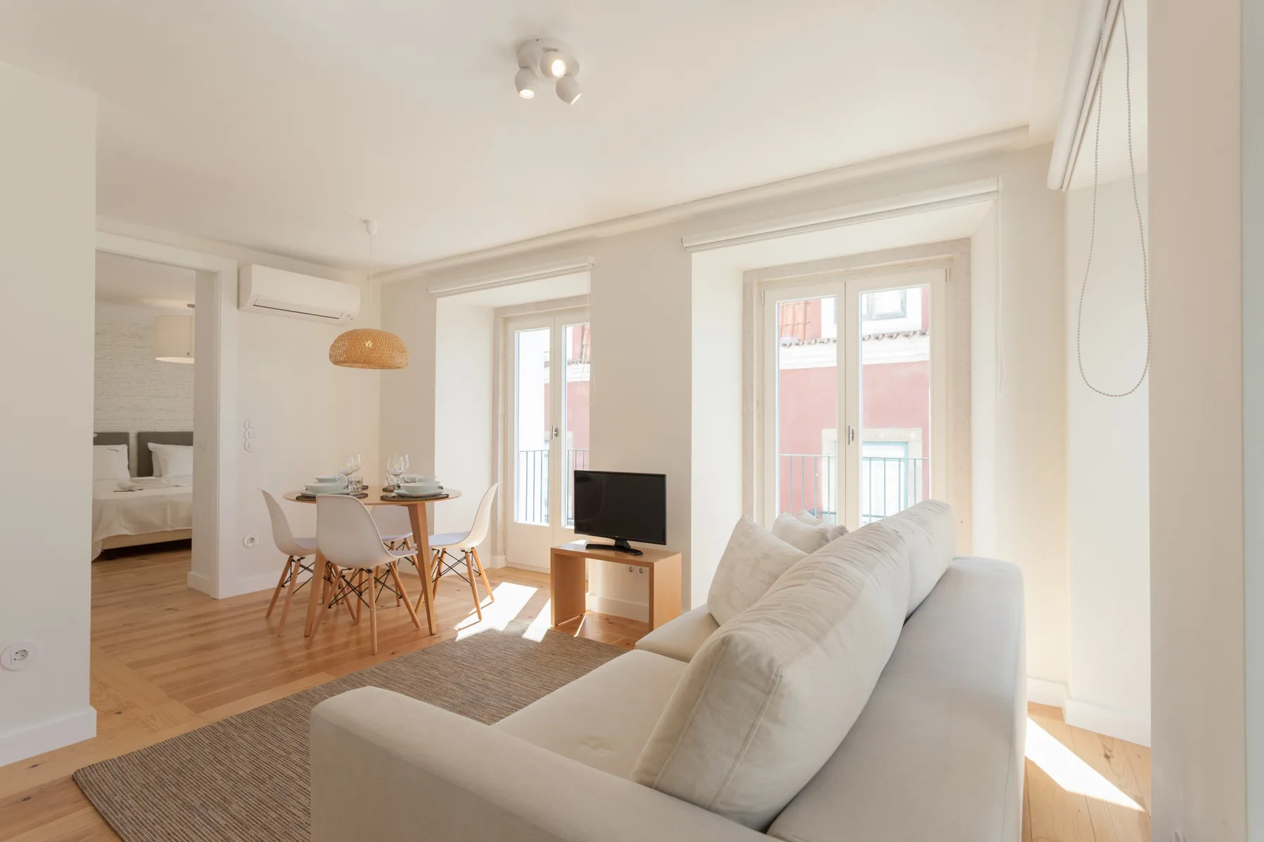 A bright living and dining area with seating beside tall windows.