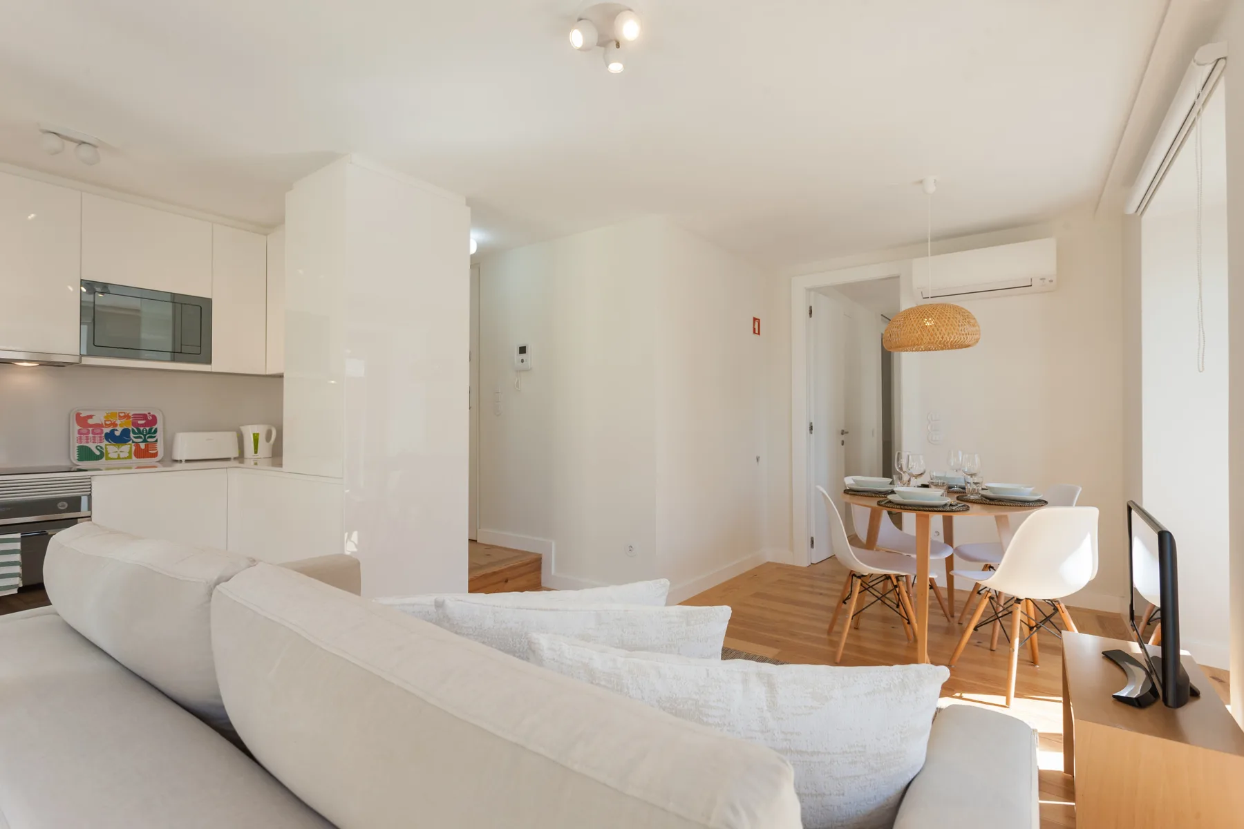 An open-plan living and dining area with a kitchen and white seating.