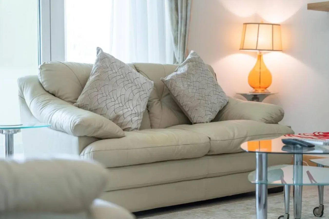 A living room seating area with a light-colored sofa and a lit table lamp.