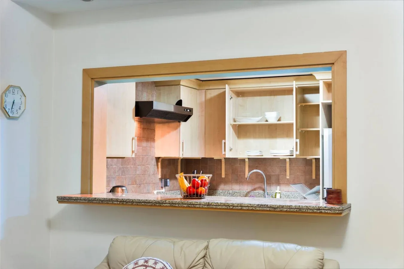 A kitchen is visible through a wide pass-through, with cabinets and a counter.