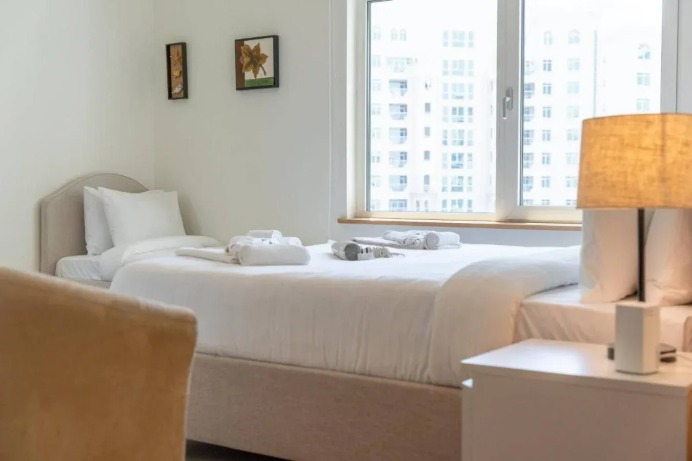 A bright bedroom with a neatly made bed beside a large window.