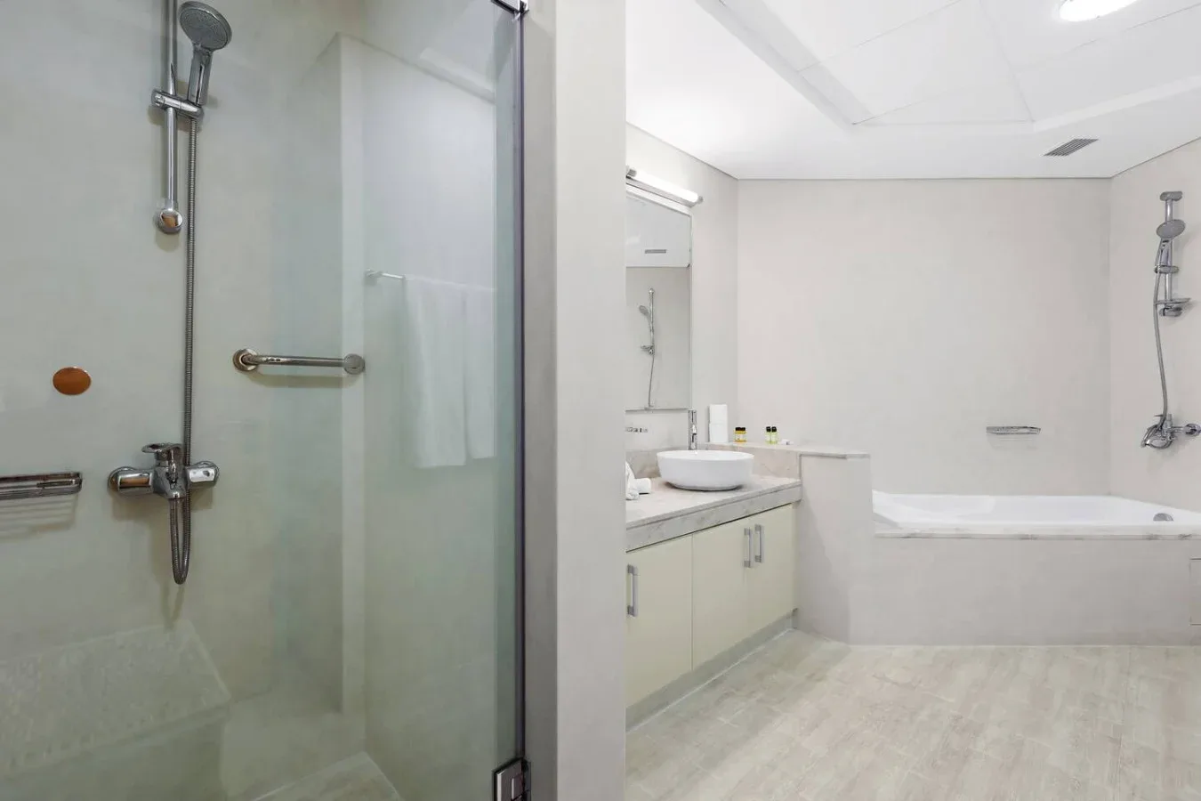 A bright bathroom with a glass shower and a bathtub beside the vanity.