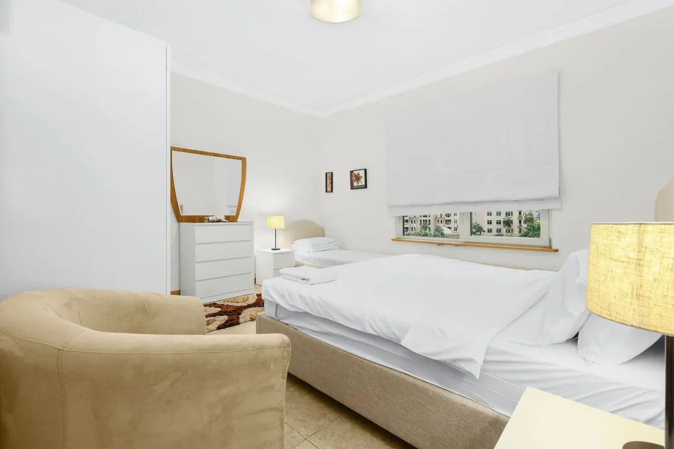 A bright bedroom with a bed and a beige armchair.