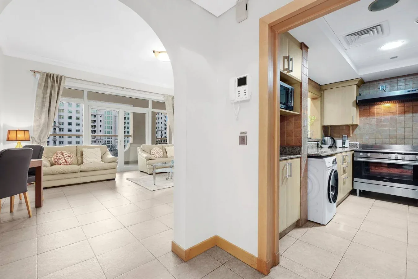 A living area opens onto a compact kitchen with tiled floors and light cabinetry.
