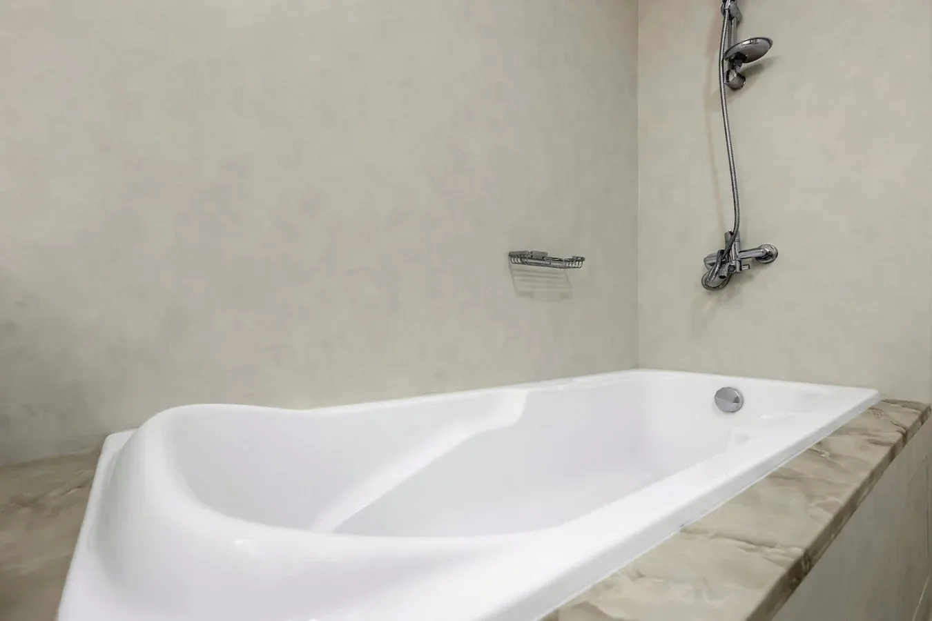 A white bathtub sits beneath a wall-mounted shower.