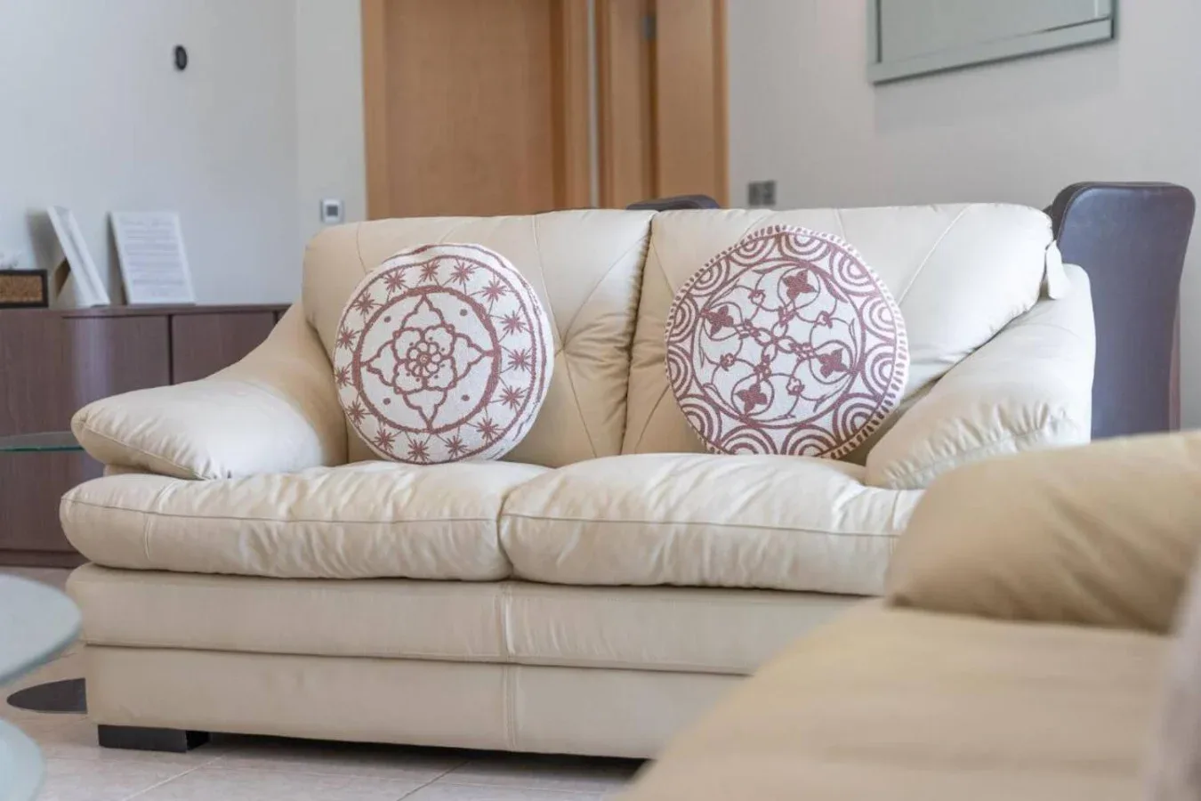 A living room with a cream-colored sofa and patterned cushions.