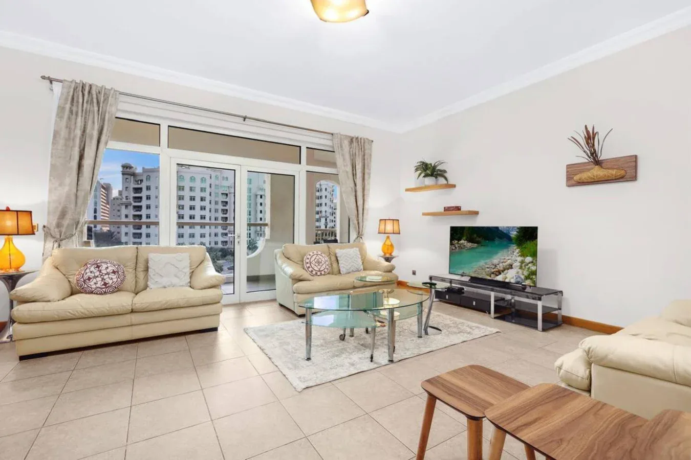 A bright living room with seating, a glass coffee table, and a television.