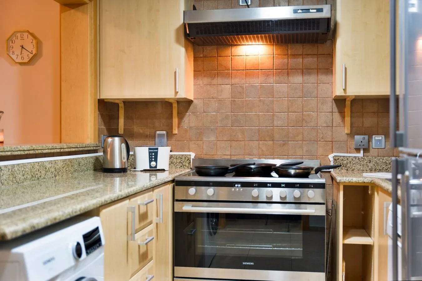 A kitchen with a stove beneath a range hood and tiled backsplash.