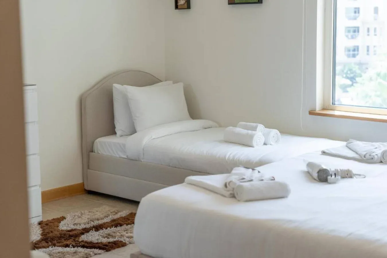 A bright bedroom with two beds dressed in white linens.