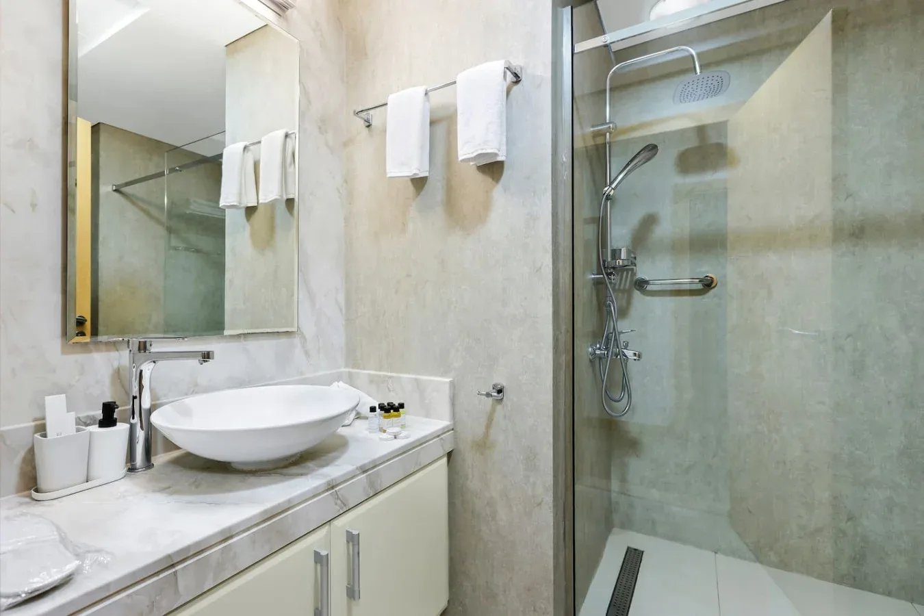 A bathroom vanity with a sink and mirror beside a glass shower.