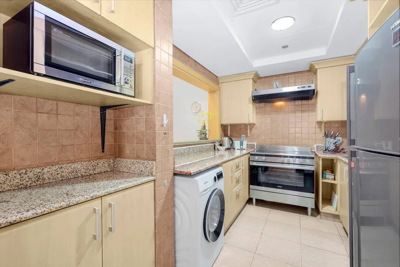 A kitchen with beige cabinets, a countertop, and cooking appliances.