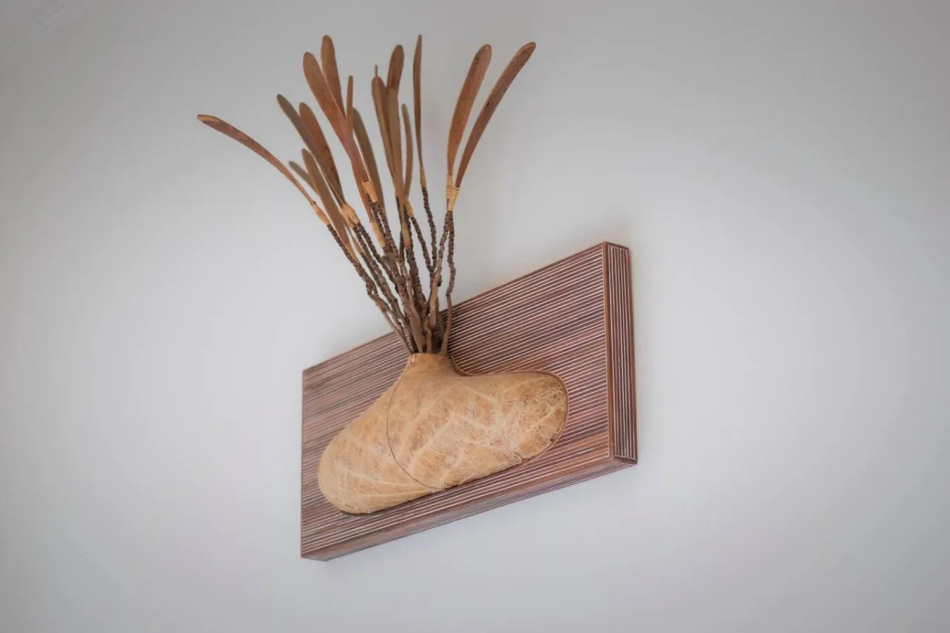 Wall-mounted decorative artwork features a pale sculptural form and dried branches.