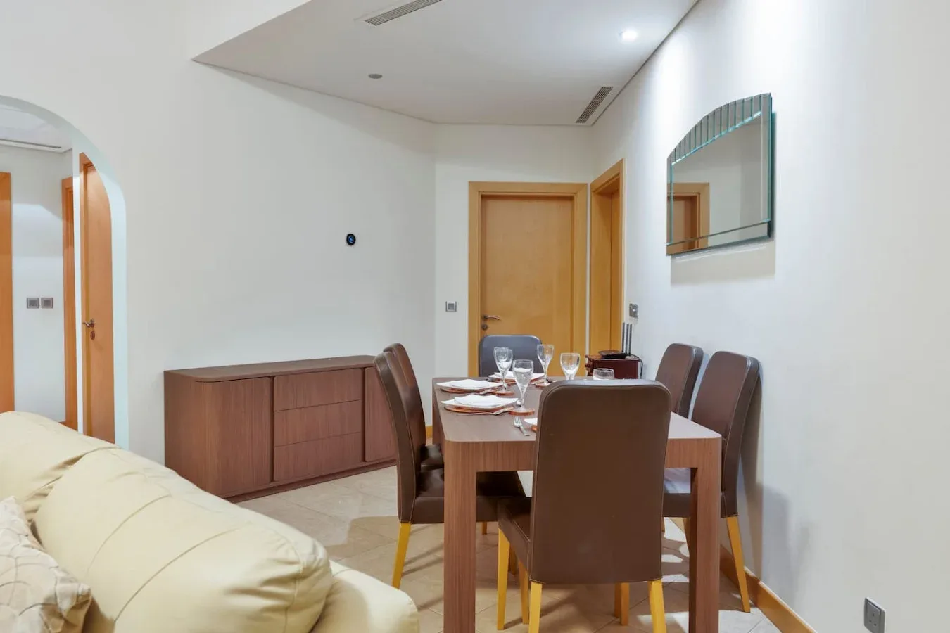 A dining area with a wooden table and brown seating beside a living room.