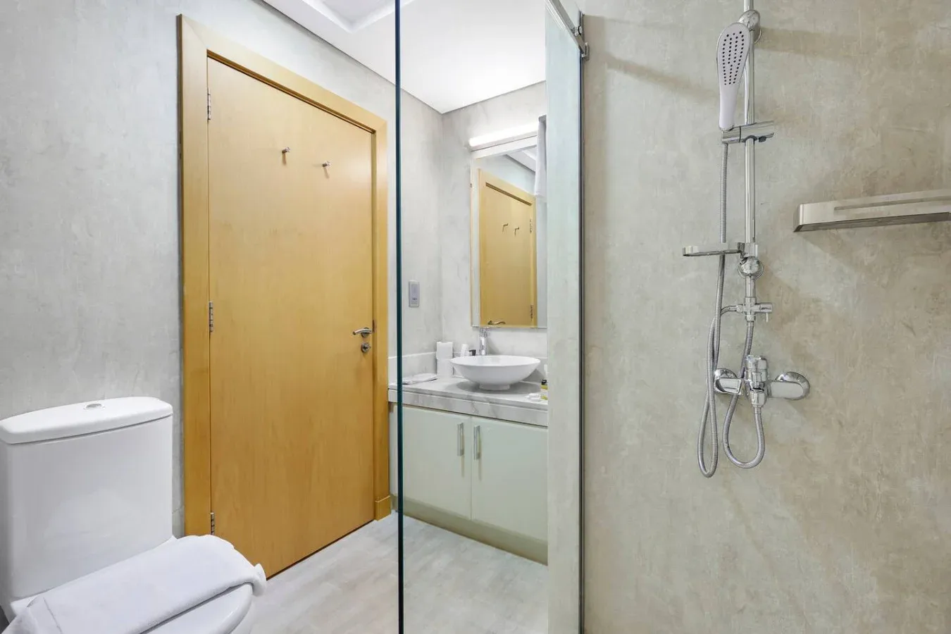 A bathroom with a glass shower, sink, and wooden door.