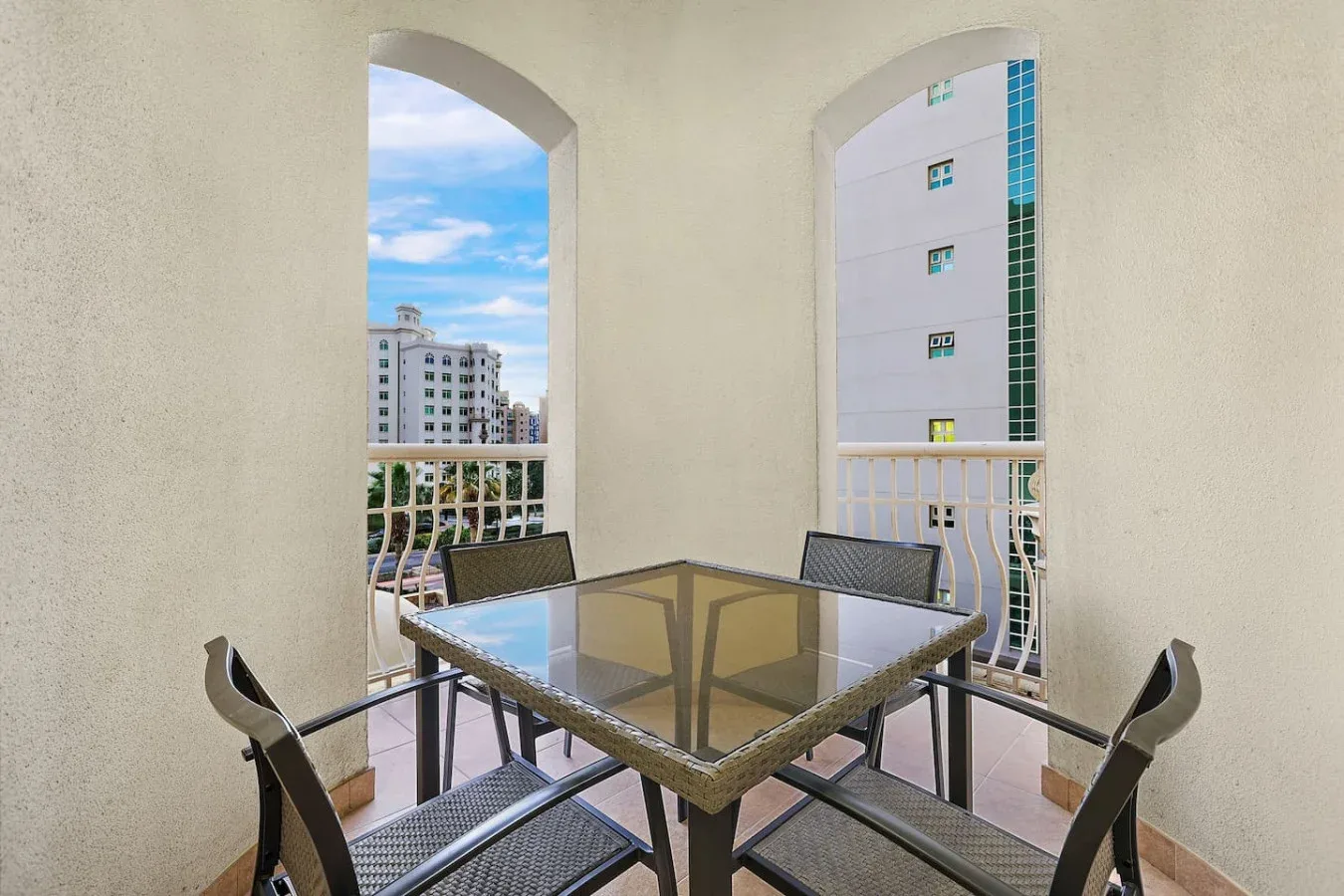 A balcony dining area with a glass-top table and city buildings visible outside.