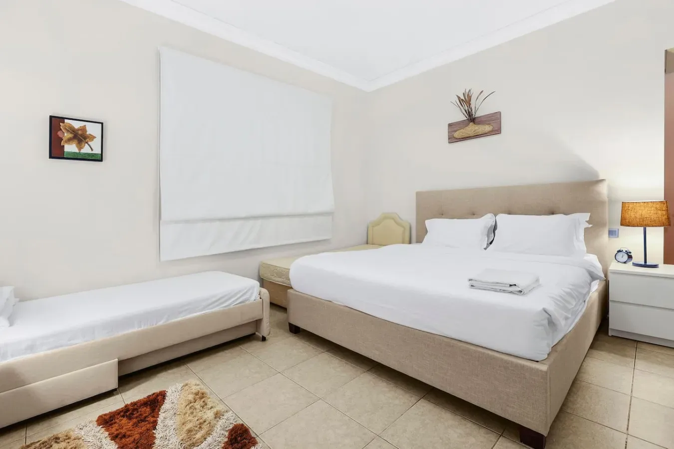 Un dormitorio luminoso con una cama grande y una cama individual al lado.