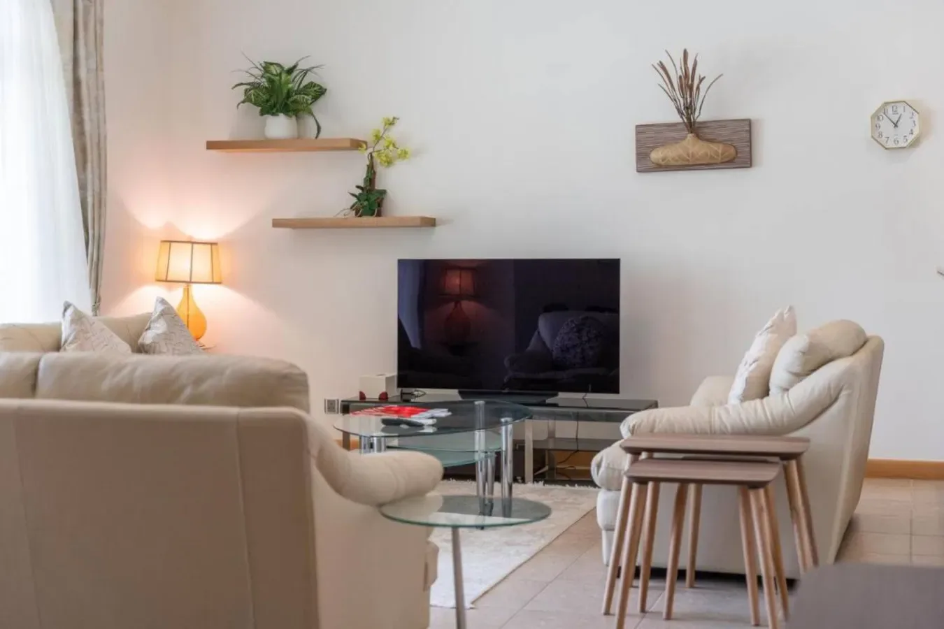 A living room with seating, a glass coffee table, and a television.