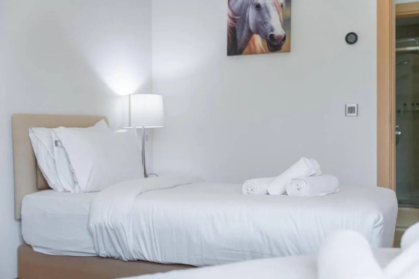 A bedroom with a neatly made bed and a lamp beside it.