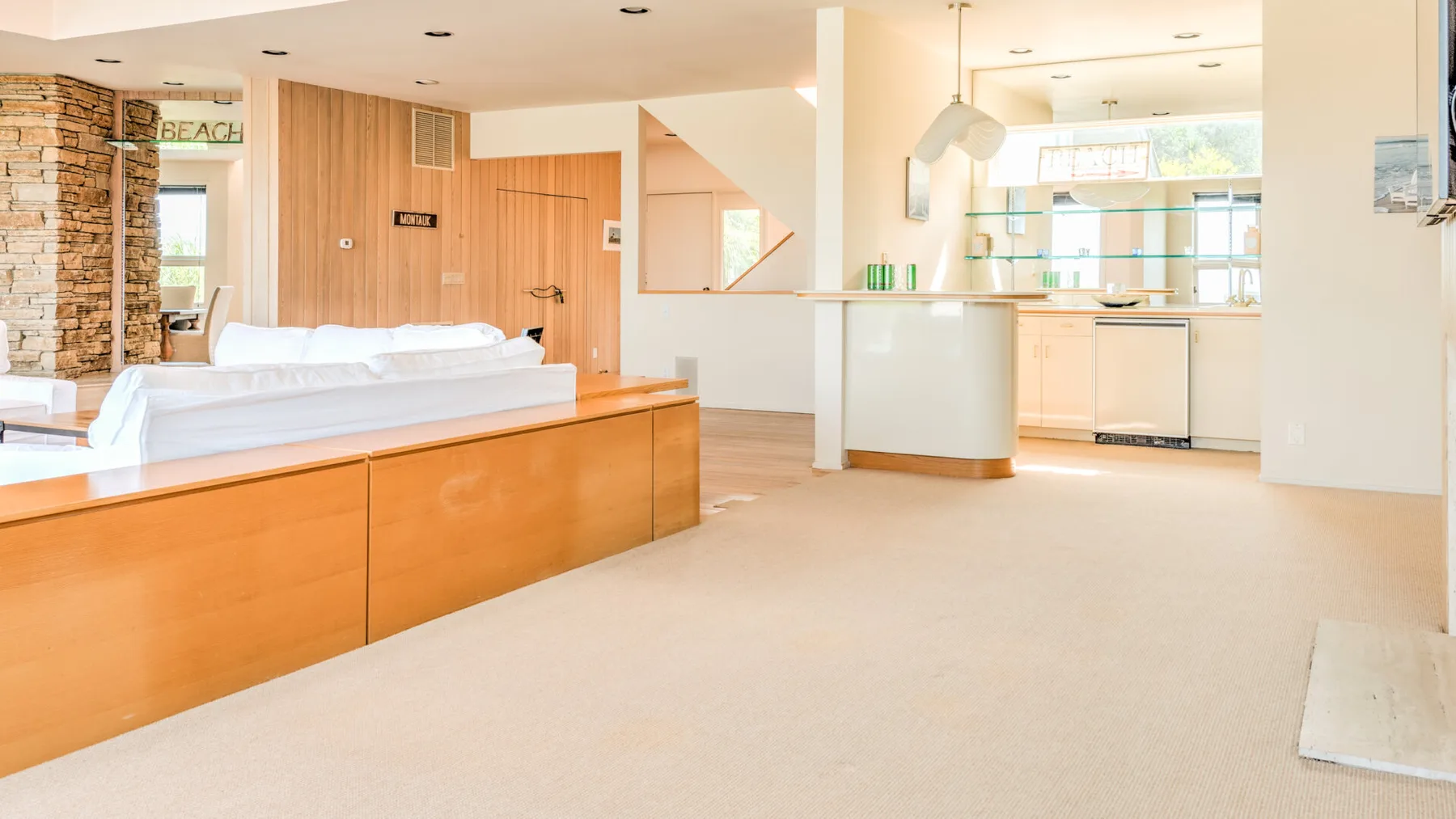 Una habitación luminosa y abierta con una barra larga de madera y una zona de cocina.