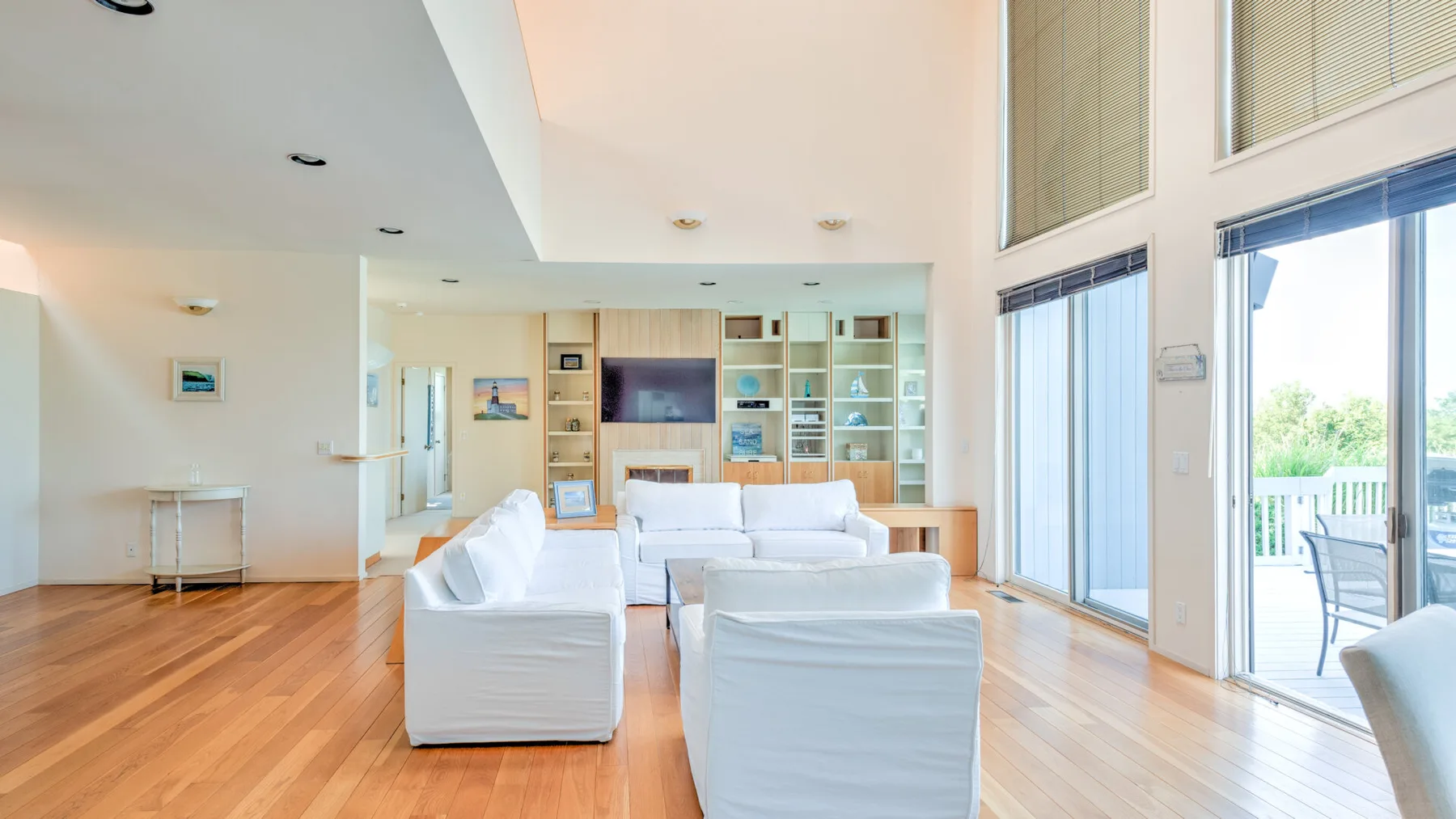 Una sala luminosa con asientos blancos y grandes ventanales que dan a un patio.