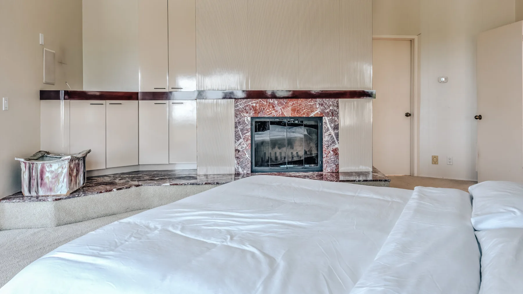 Un dormitorio con una cama grande frente a una chimenea y armarios empotrados.